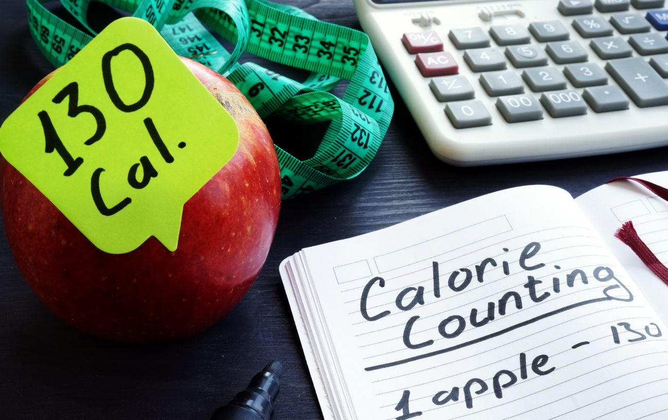 An apple, calculator, and a notebook.