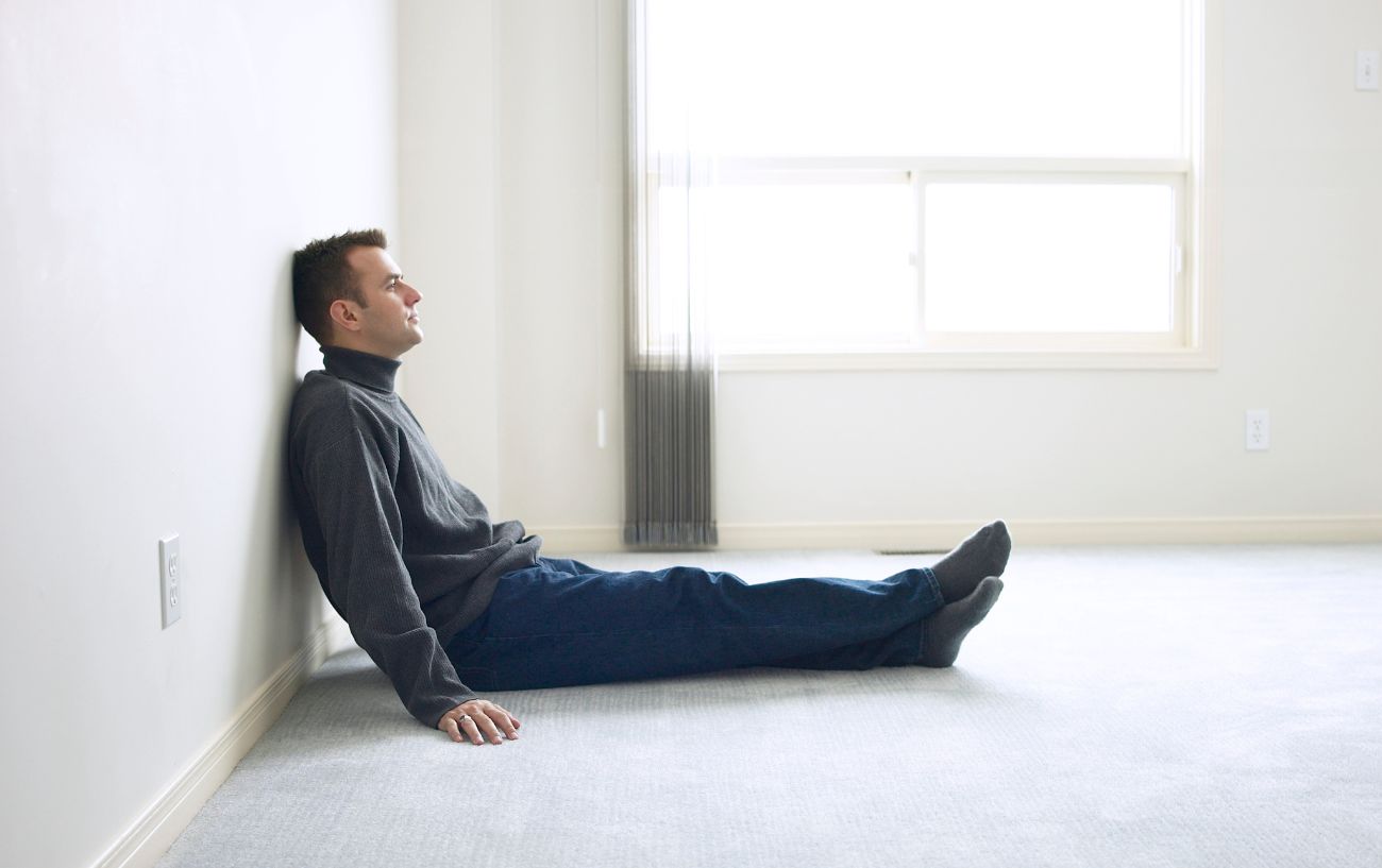 A tired man sitting on the floor.