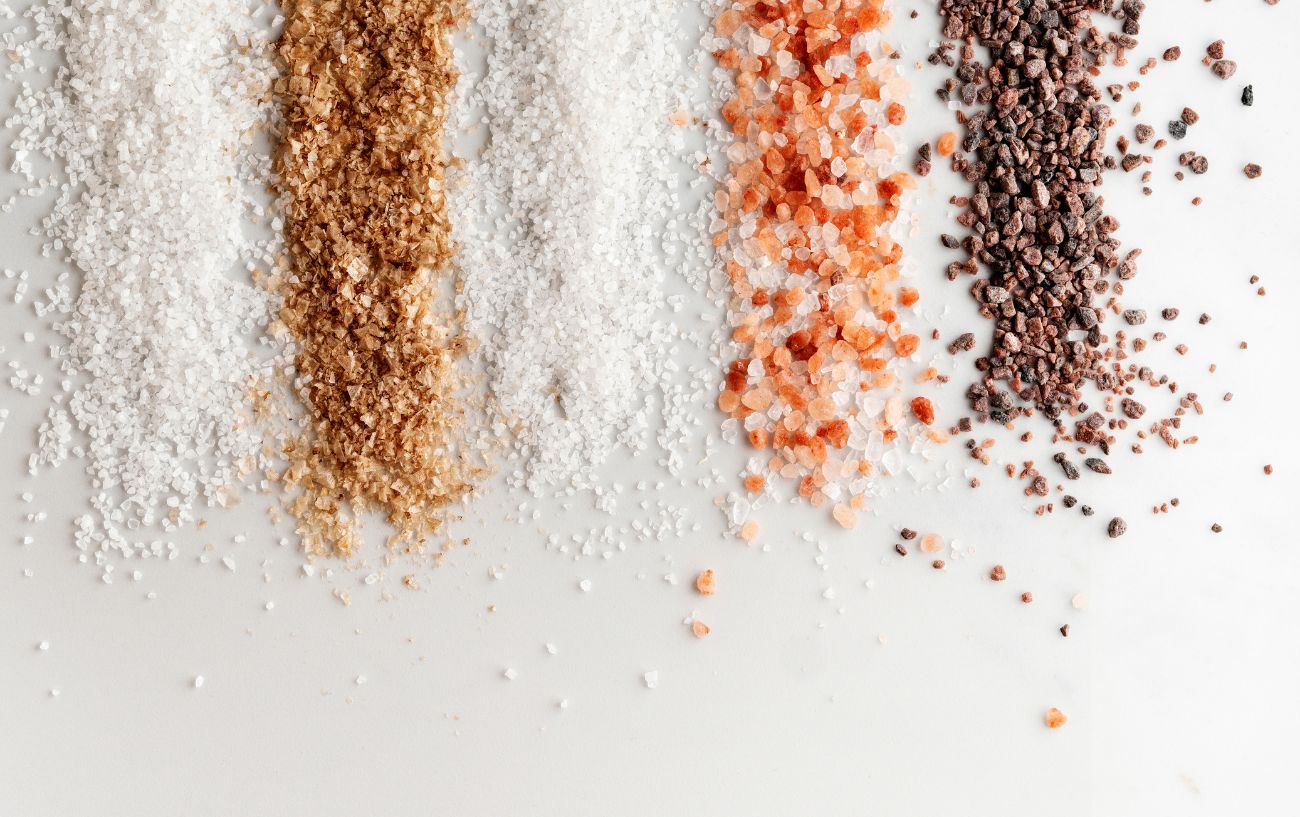 A variety of different salts spread on a table. 
