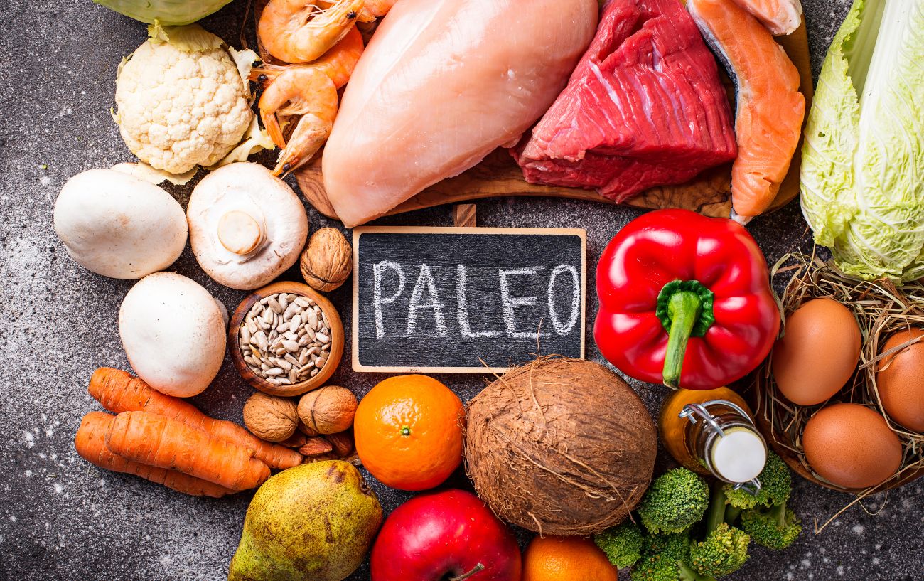 A sign that says Paleo is surrounded by foods such as vegetables, meats, and eggs.