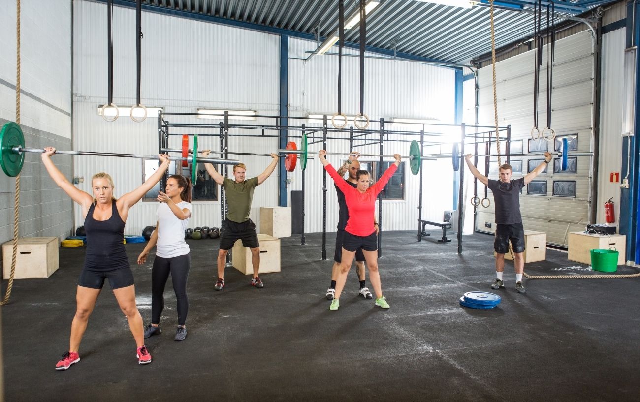 A gym class of people doing overhead presses.