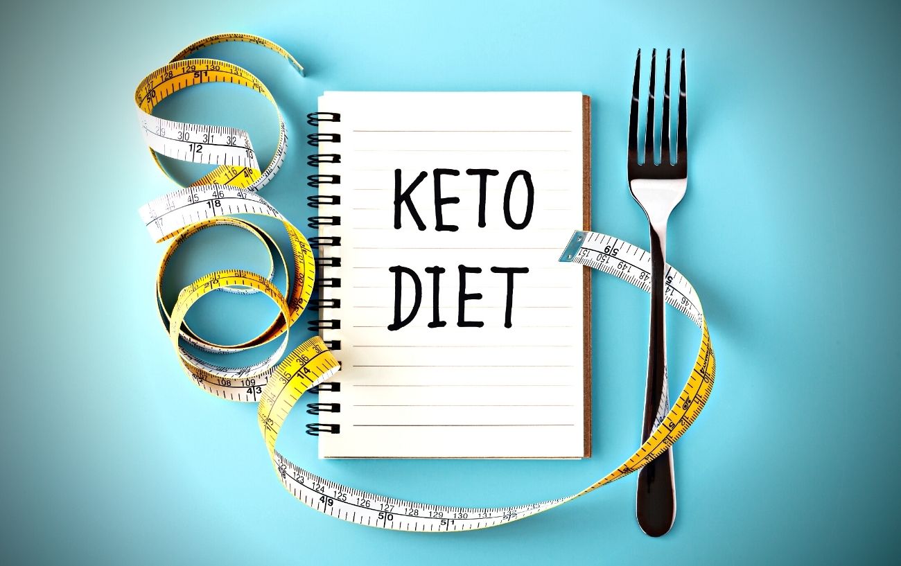 A notebook that says keto diet, a fork and a measuring tape.